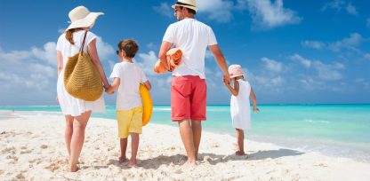 a man and two children are walking on the beach.