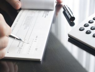 a person filling out a form next to a calculator.