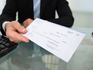 a man in a suit is holding a cheque.