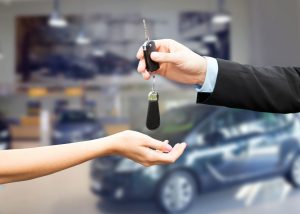 a person handing a car key to another person.