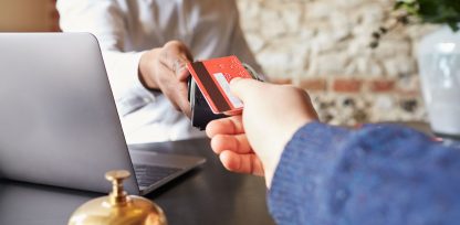 a person handing a credit card to another person.