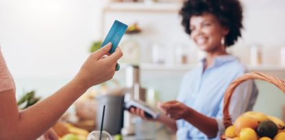 a woman holding a credit card in a kitchen.