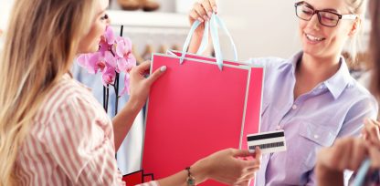 a woman holding a shopping bag and a credit card.