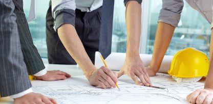 a group of people standing around a blueprint.